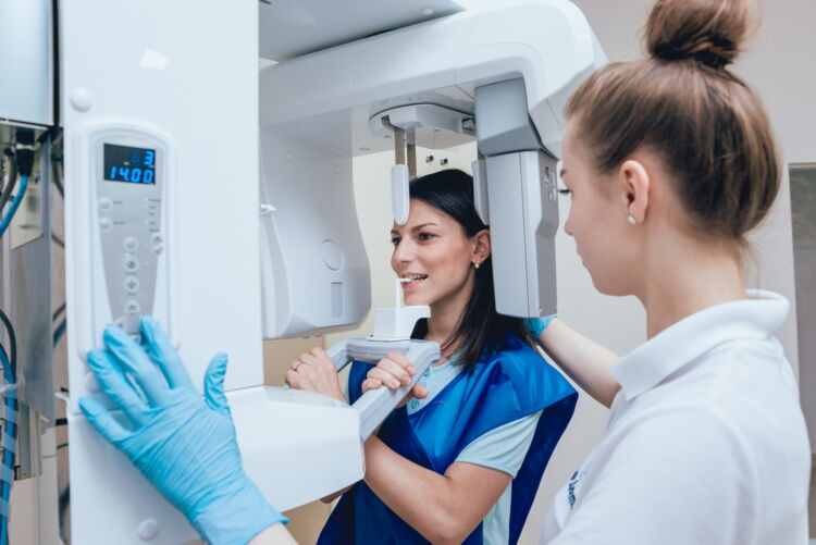 Patientin wird von zahnmedizinischer Assistentin in 360° Röntgengerät vorbereitet