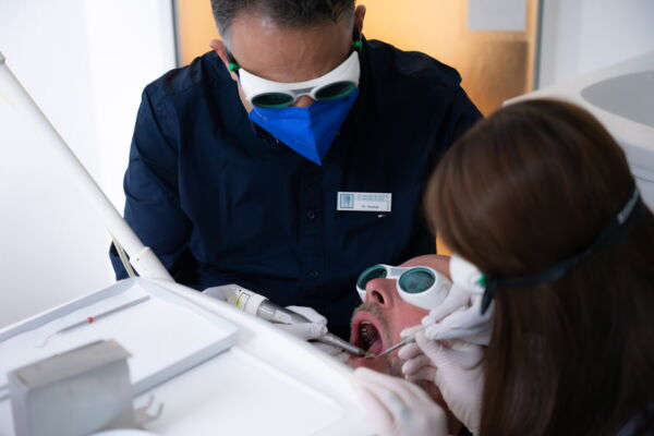 Zahnarzt mit Helferin führt Laserbehandlung durch