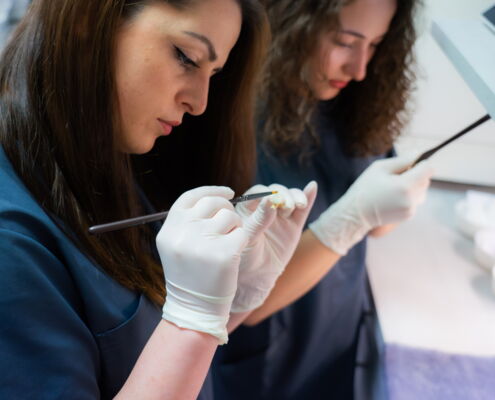 2 Zahnarzthelferinnen bei Feinarbeiten an einem keramischen Zahnersatz