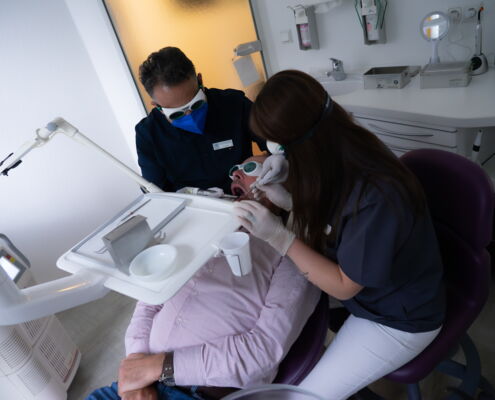 Zahnarzt mit Helferin führt Laserbehandlung durch