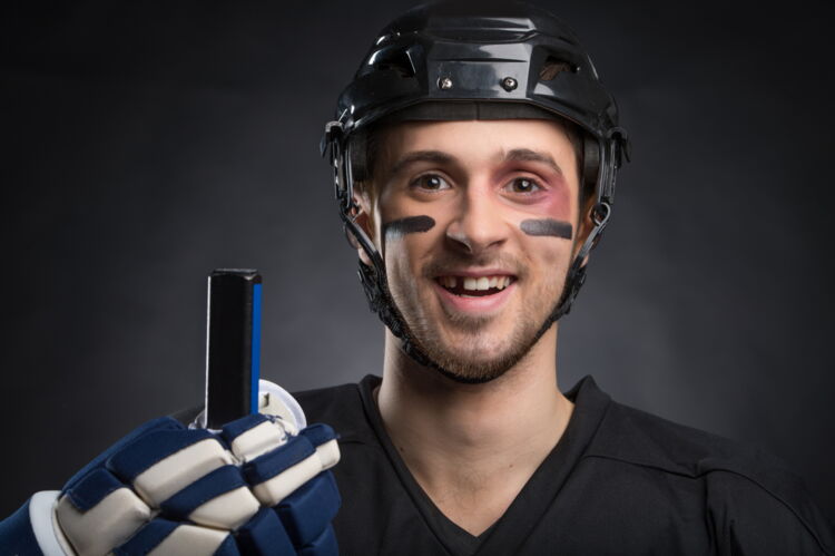 Lächelnder Eishockeyspieler in voller Montour mit einer deutlich sichtbaren Zahnlücke